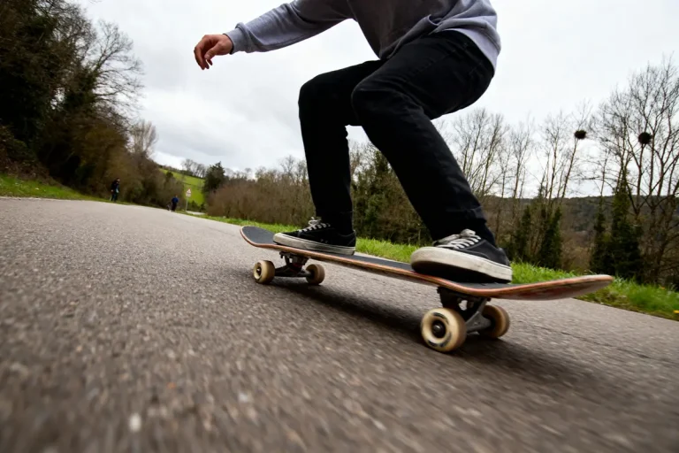 Personne sur un skateboard surf descendant une route bordée d'arbres en forêt