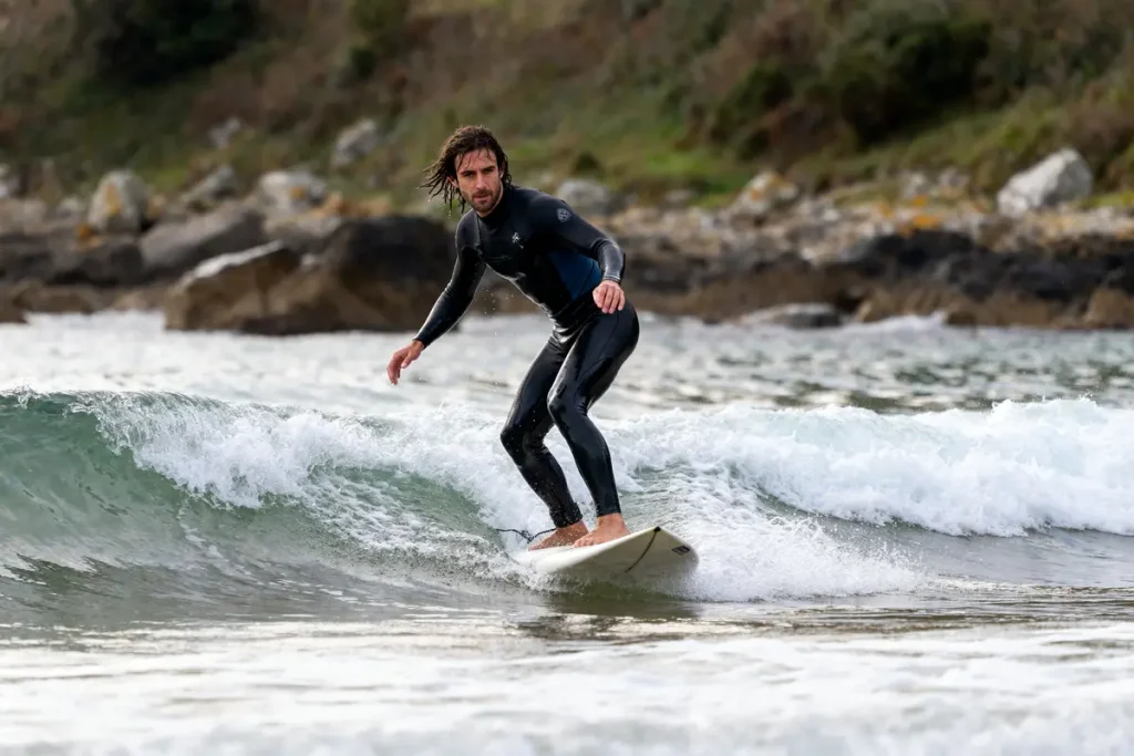 Surfeur sur une petite vague, performance de Hugues Oyarzabal en surf sur l'océan.
