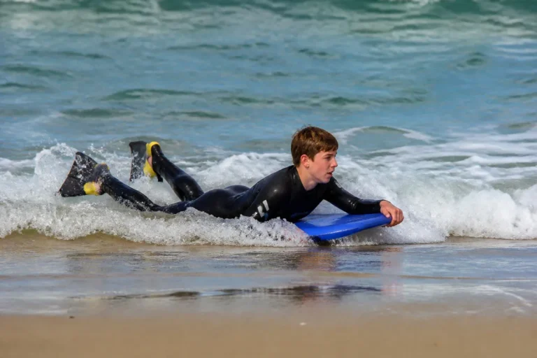 Jeune bodyboarder avec palmes prenant une petite vague près du bord